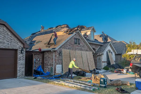 A roofer refixing displaced clay tiles on a pitched roof